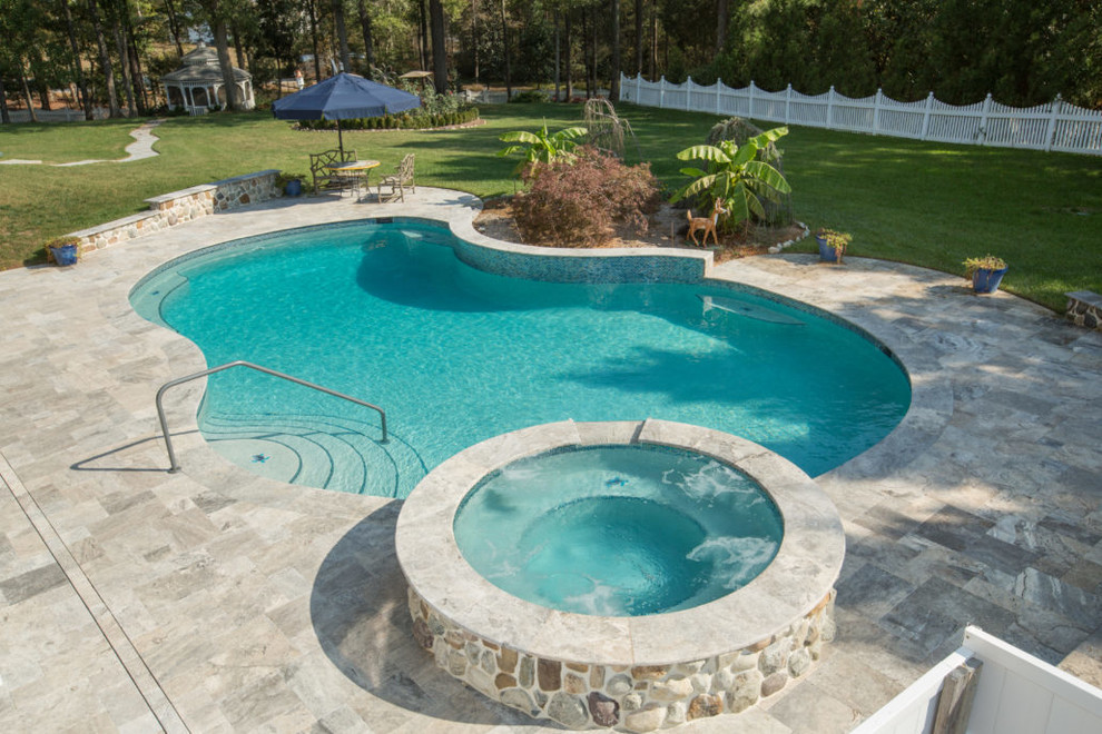 Imagen de piscinas y jacuzzis elevados actuales de tamaño medio redondeados en patio trasero con adoquines de piedra natural