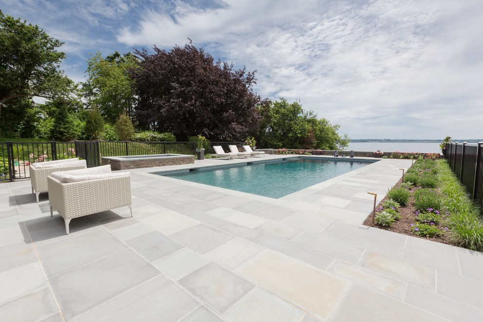 Modelo de piscinas y jacuzzis clásicos extra grandes rectangulares en patio trasero con adoquines de piedra natural