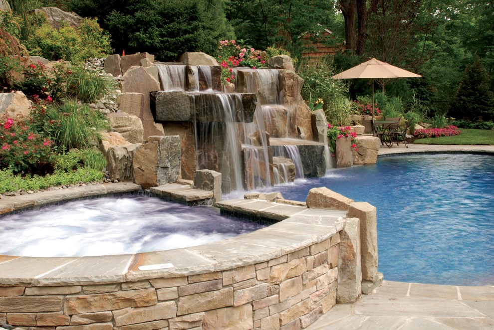 Пример оригинального дизайна: большой бассейн произвольной формы на заднем дворе в классическом стиле с джакузи и покрытием из каменной брусчатки