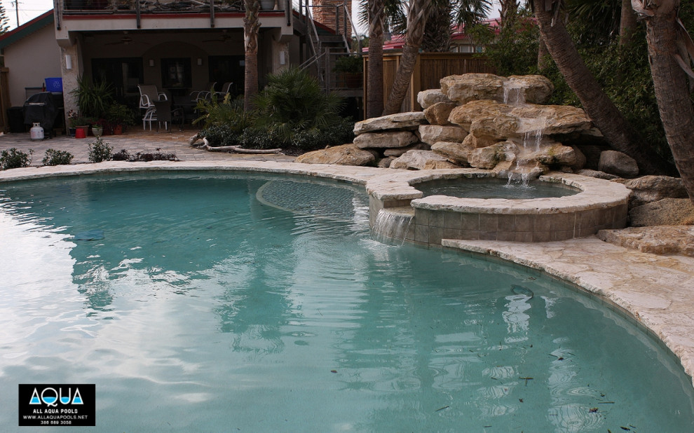 Foto di una piscina tropicale personalizzata con una vasca idromassaggio