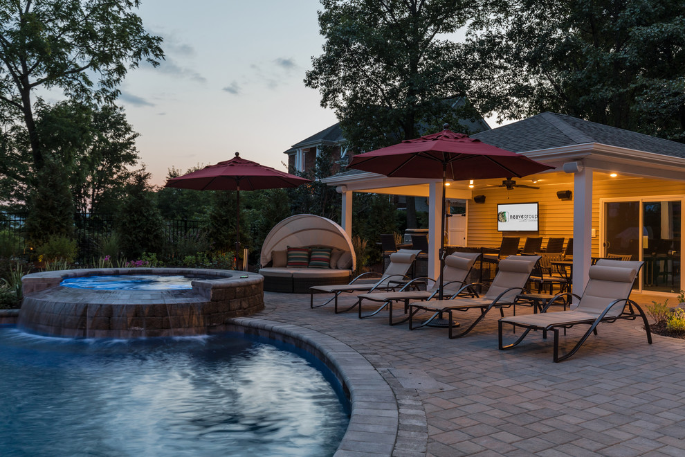 This is an example of a medium sized rustic back custom shaped swimming pool in New York with a water slide and brick paving.