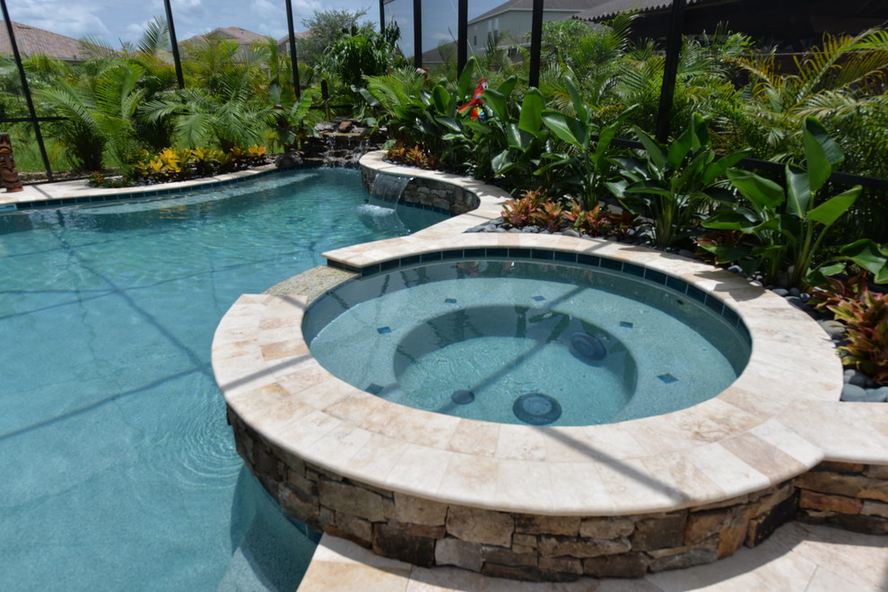 Foto di un'ampia piscina naturale stile marinaro personalizzata dietro casa con una vasca idromassaggio e pavimentazioni in pietra naturale