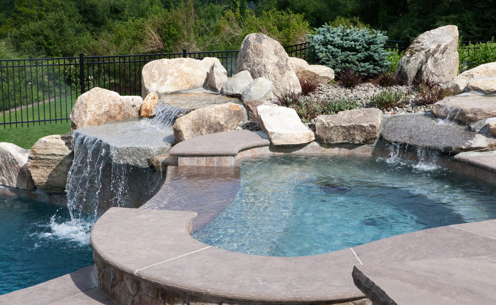 Design ideas for a medium sized classic back custom shaped natural swimming pool in Boston with a water feature and natural stone paving.