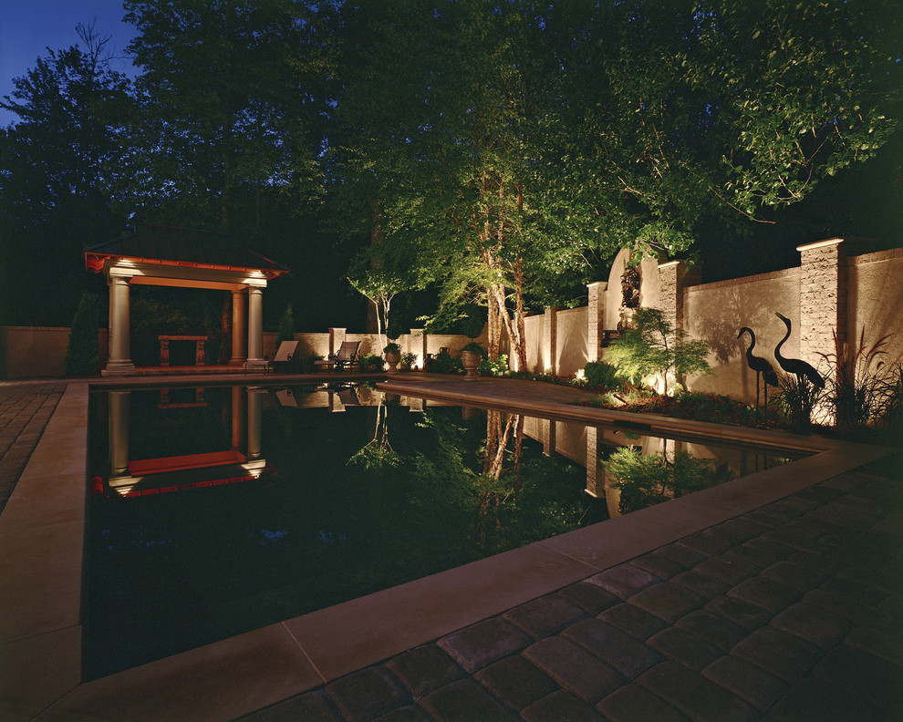 Foto de piscina tradicional rectangular en patio trasero con adoquines de piedra natural