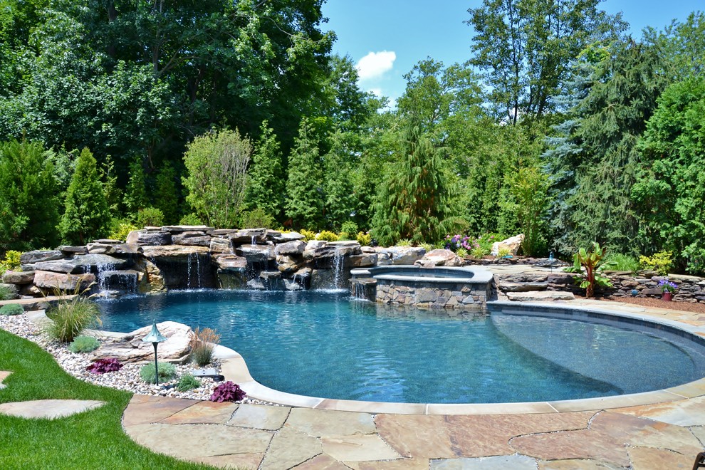 Exemple d'une grande piscine naturelle tendance sur mesure avec des pavés en pierre naturelle.