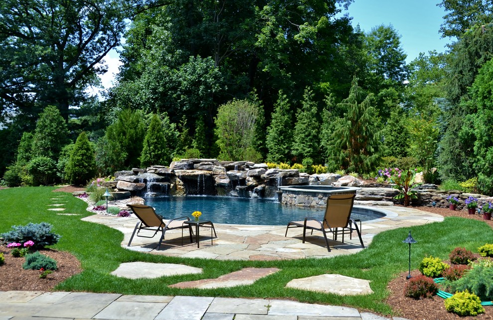 Inspiration for a large contemporary custom shaped natural swimming pool in New York with natural stone paving.