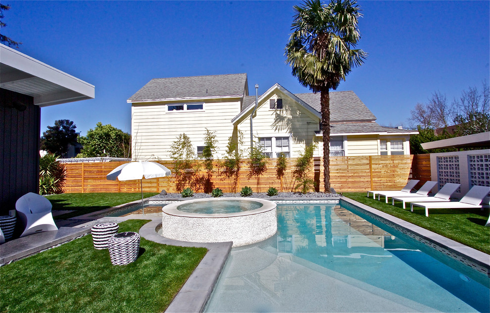 Modelo de piscinas y jacuzzis alargados vintage de tamaño medio en forma de L en patio trasero con adoquines de piedra natural