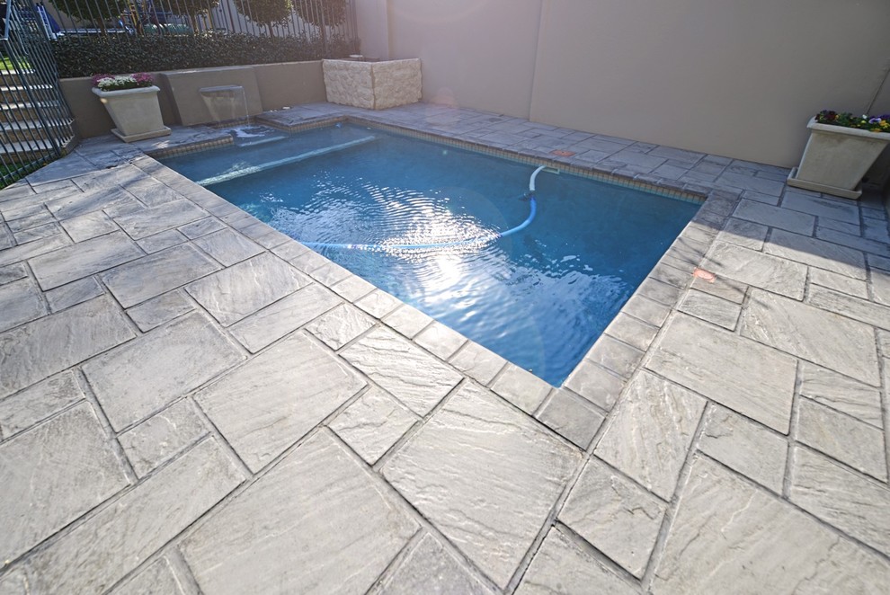 Foto di una piscina classica rettangolare di medie dimensioni e dietro casa con pavimentazioni in cemento