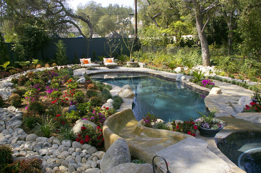 Пример оригинального дизайна: большой бассейн произвольной формы на заднем дворе в классическом стиле с покрытием из каменной брусчатки и водной горкой