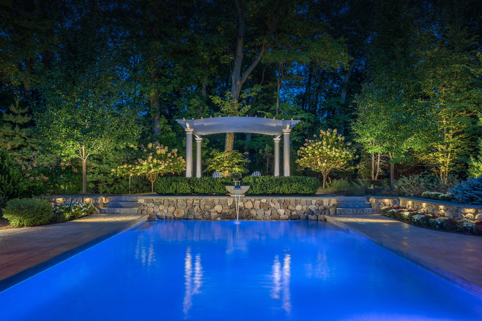 Imagen de piscina con fuente natural tradicional de tamaño medio rectangular en patio trasero con suelo de hormigón estampado