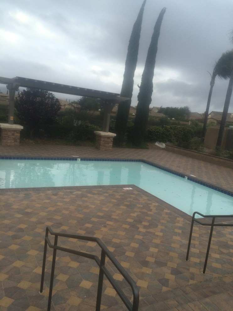 Diseño de piscina clásica renovada de tamaño medio en forma de L en patio trasero con adoquines de piedra natural