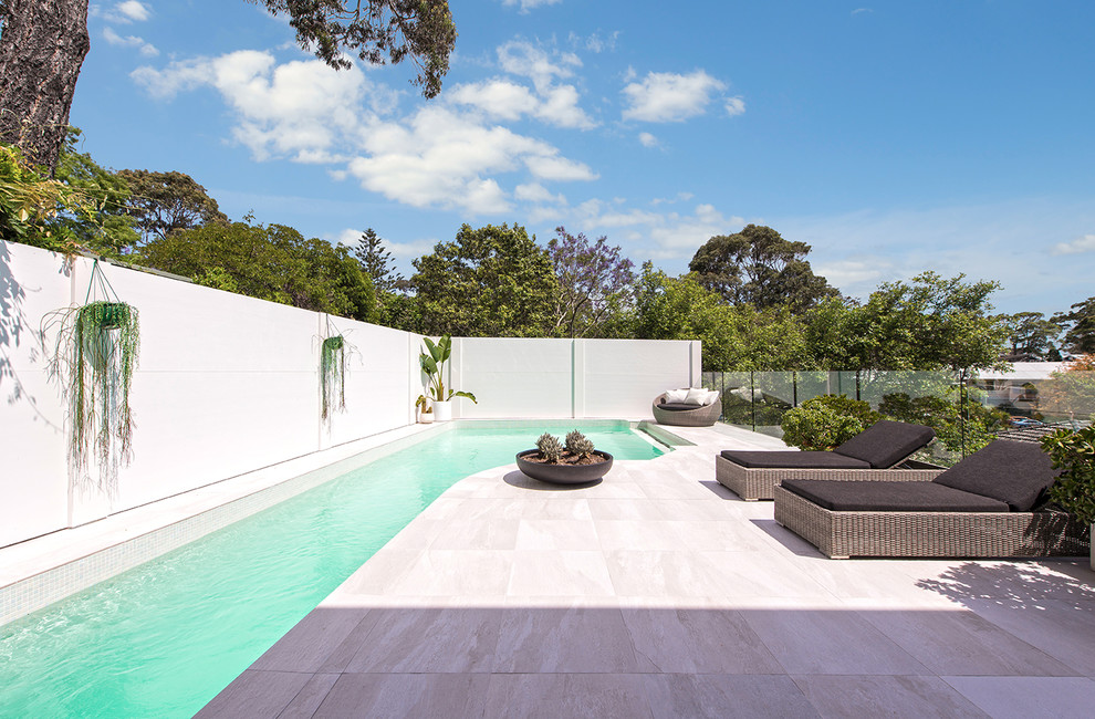 Foto de piscina alargada moderna a medida en patio trasero con suelo de baldosas