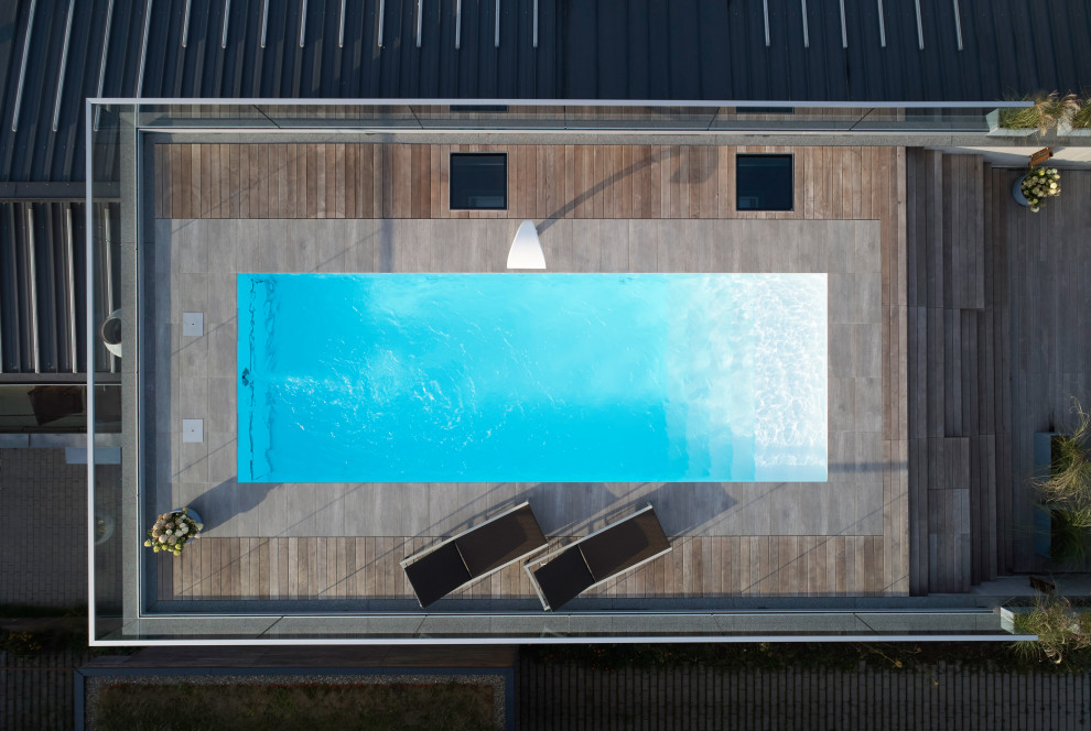 Aménagement d'une piscine contemporaine de taille moyenne et rectangle avec une terrasse en bois.