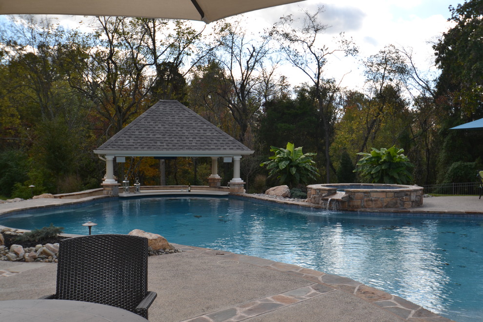Foto di una grande piscina naturale classica personalizzata dietro casa con una vasca idromassaggio e graniglia di granito