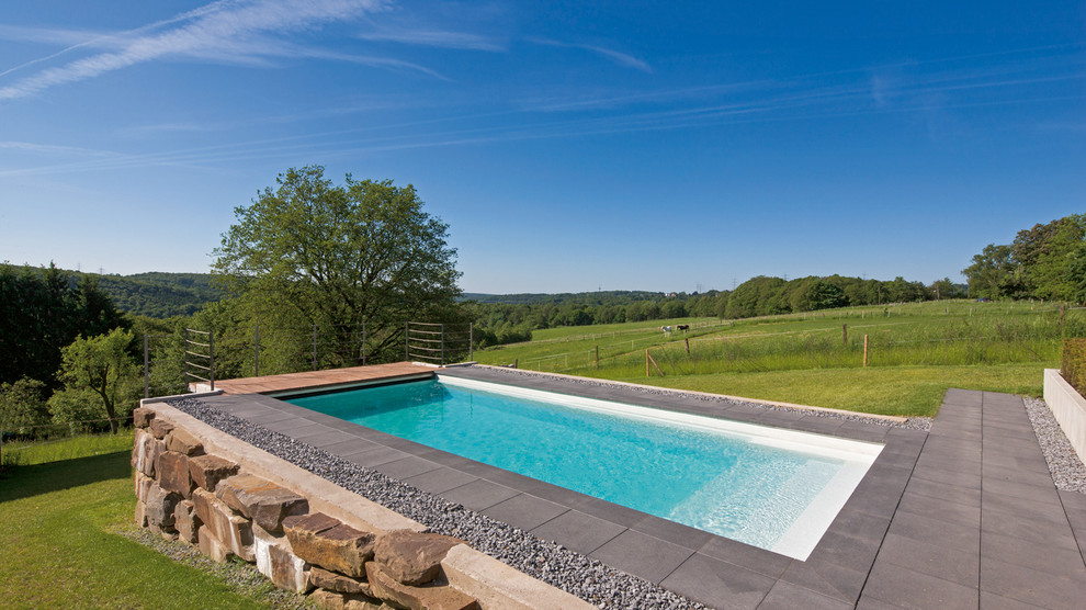 Ejemplo de piscina rústica pequeña rectangular con losas de hormigón