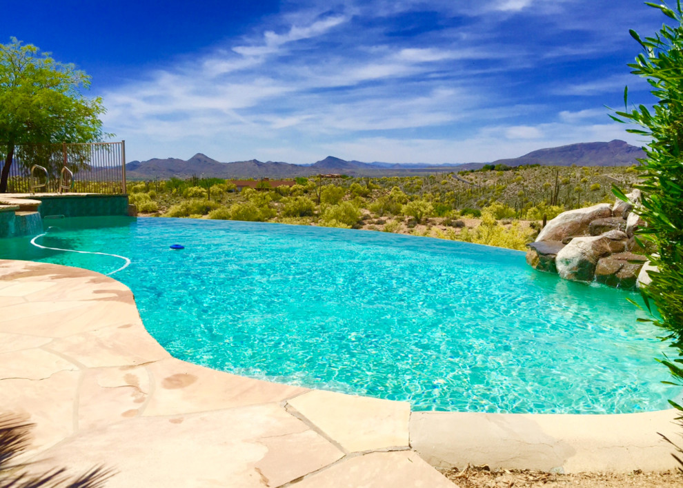 Exemple d'une grande piscine à débordement et arrière sud-ouest américain sur mesure avec un bain bouillonnant et du béton estampé.