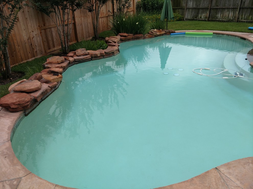 Idee per una piscina naturale tropicale personalizzata di medie dimensioni e dietro casa con fontane