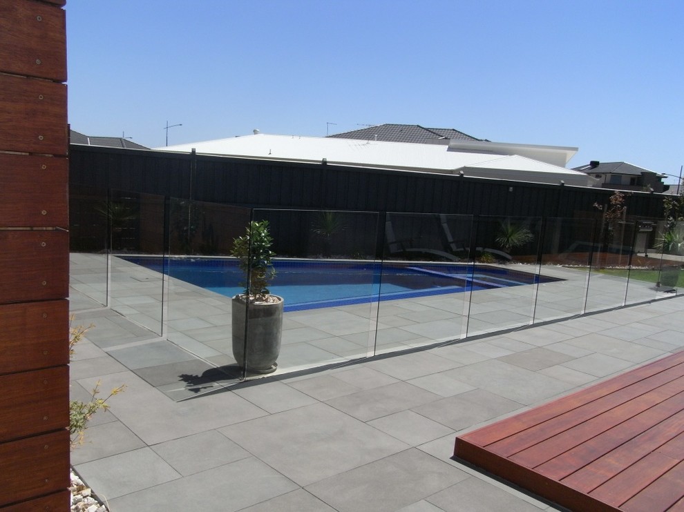Ejemplo de piscina alargada moderna de tamaño medio rectangular en patio trasero con adoquines de piedra natural