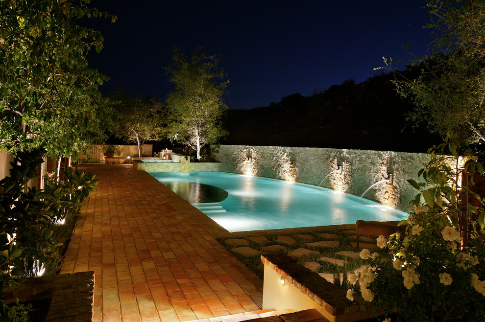 Ejemplo de piscina mediterránea de tamaño medio rectangular en patio trasero con adoquines de ladrillo