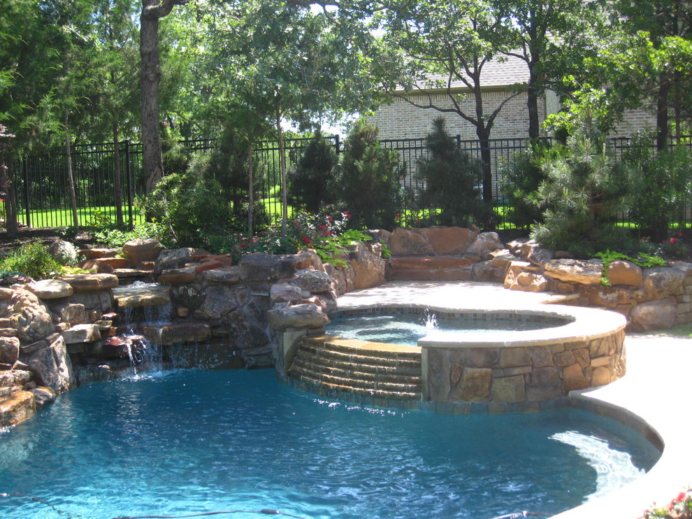 Foto di una grande piscina monocorsia tradizionale a "C" dietro casa con fontane e pavimentazioni in cemento