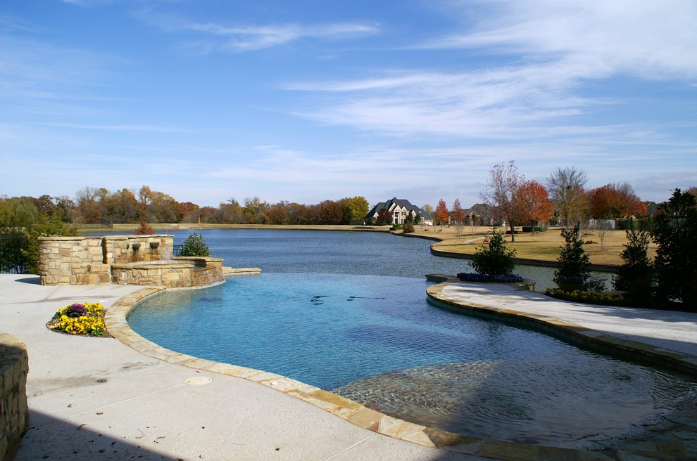Imagen de piscina con fuente infinita mediterránea grande a medida en patio trasero con adoquines de hormigón