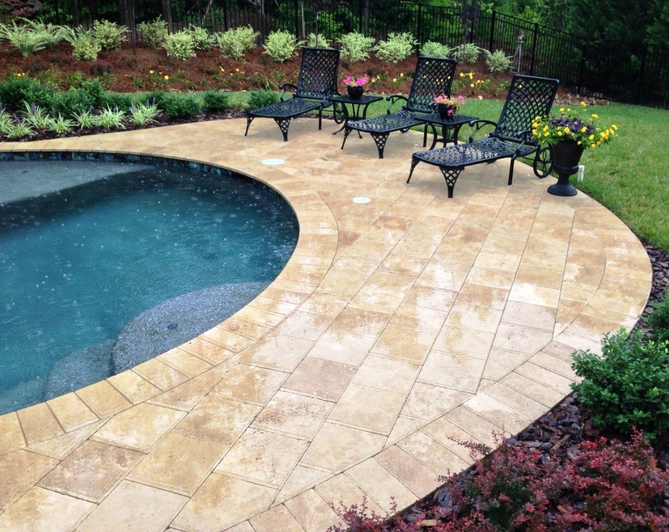 This is an example of a rustic back natural swimming pool in Charlotte with natural stone paving.