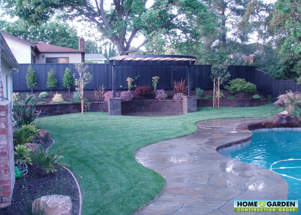 Photo of a world-inspired back custom shaped natural swimming pool in San Francisco with natural stone paving.