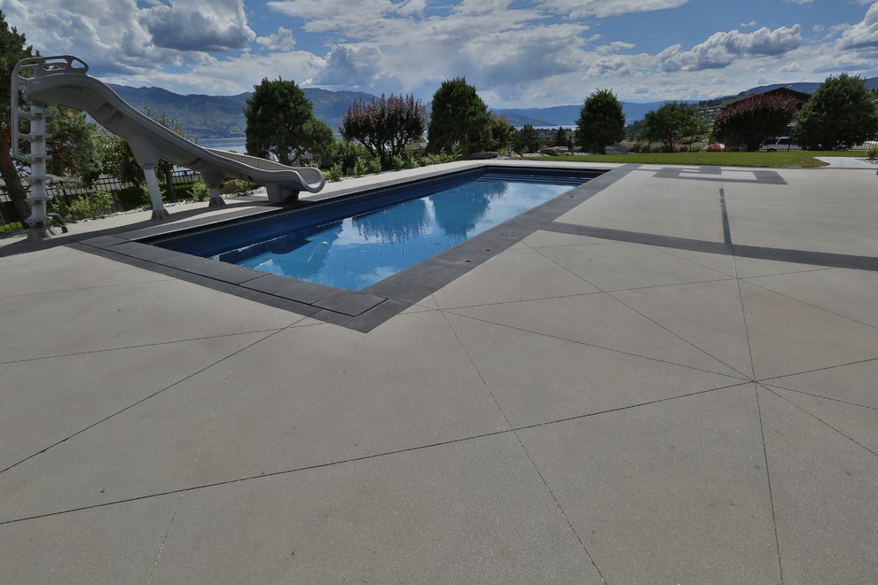 На фото: большой прямоугольный бассейн на заднем дворе в современном стиле с водной горкой и покрытием из бетонных плит с
