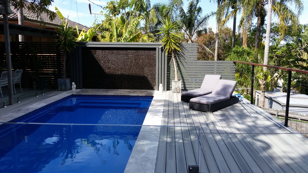 Modelo de piscina elevada contemporánea grande rectangular en patio trasero con entablado