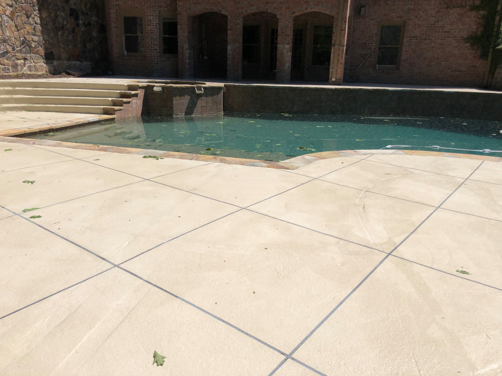 Idée de décoration pour une grande piscine hors-sol et arrière sur mesure avec un point d'eau et du béton estampé.
