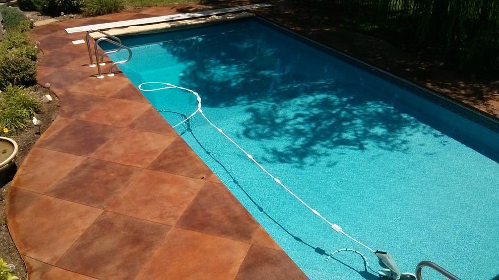 Ejemplo de piscina de tamaño medio redondeada en patio trasero con losas de hormigón