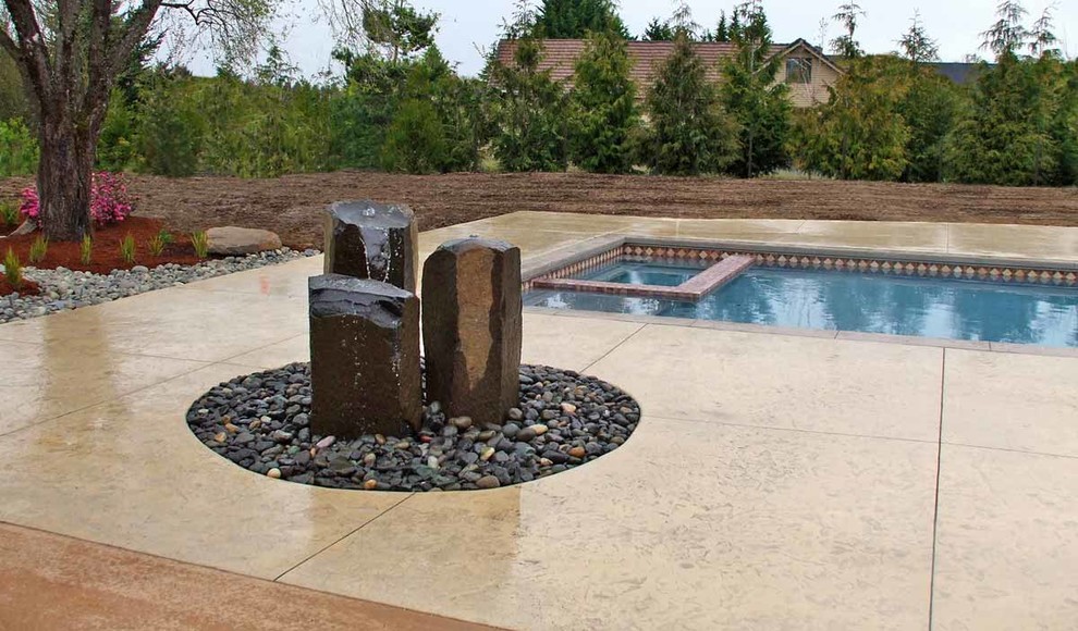 Esempio di una piscina monocorsia classica rettangolare di medie dimensioni e dietro casa con fontane e lastre di cemento