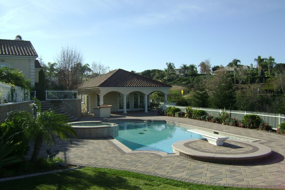 Photo of a large world-inspired back custom shaped natural hot tub in Los Angeles with natural stone paving.