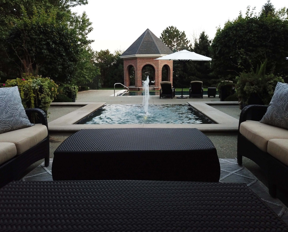 Photo of a medium sized traditional back rectangular infinity hot tub in Indianapolis with concrete paving.