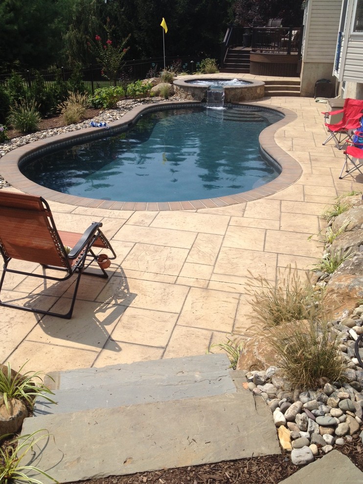 Foto di una grande piscina naturale tropicale personalizzata dietro casa con una vasca idromassaggio e pavimentazioni in pietra naturale