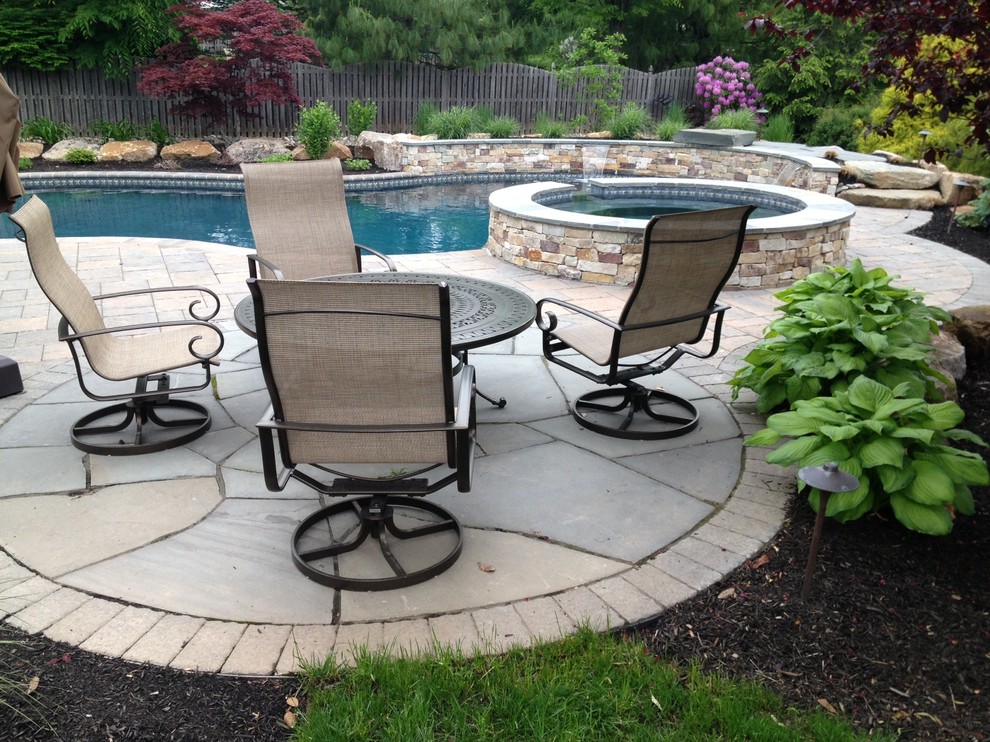 Design ideas for a large rustic back custom shaped hot tub in Philadelphia with natural stone paving.