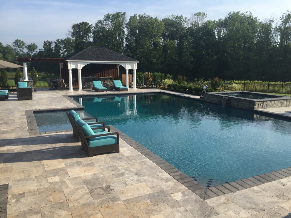На фото: большой естественный бассейн произвольной формы на заднем дворе в современном стиле с покрытием из каменной брусчатки и домиком у бассейна с