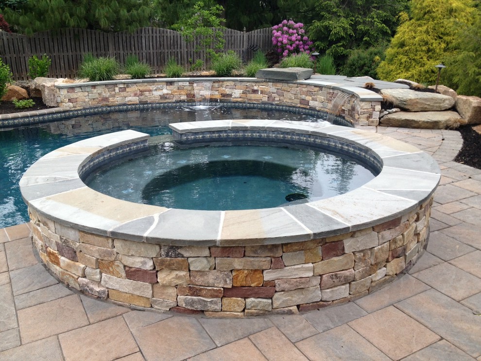 Immagine di una grande piscina naturale rustica personalizzata dietro casa con una vasca idromassaggio e pavimentazioni in pietra naturale