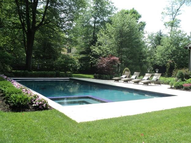 На фото: большой прямоугольный бассейн на заднем дворе в классическом стиле с покрытием из бетонных плит