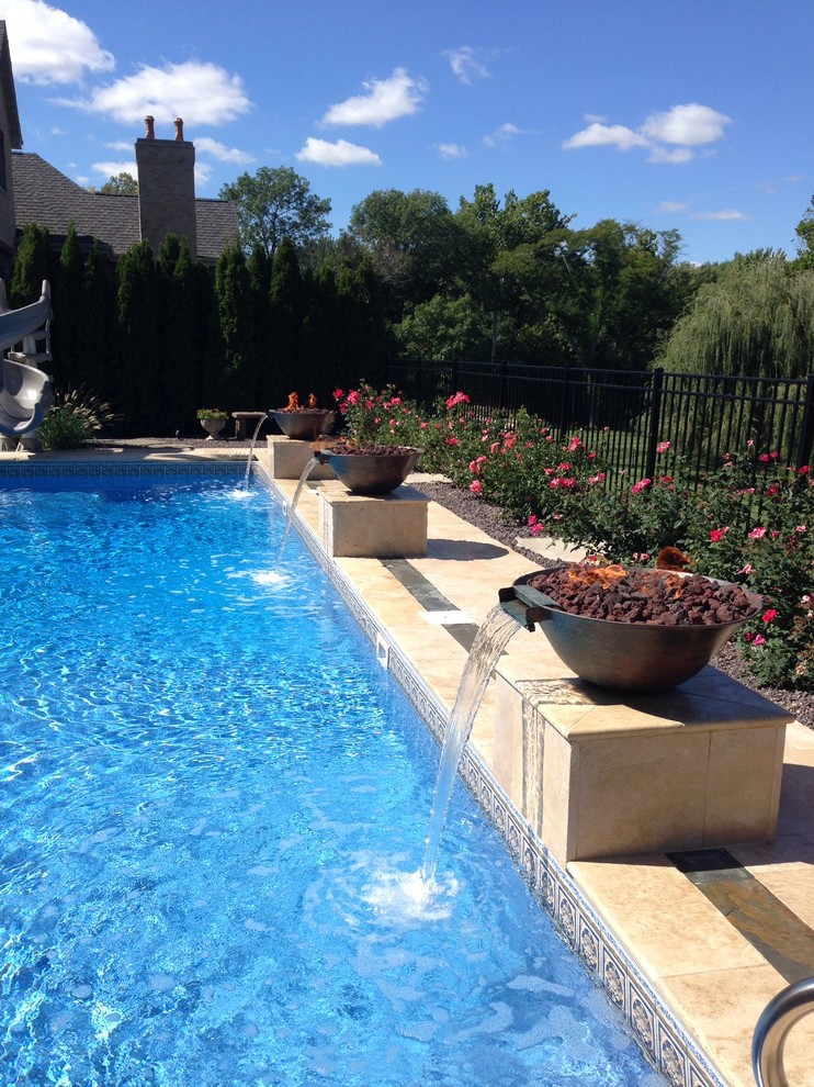 Imagen de piscina con fuente clásica grande rectangular en patio trasero con suelo de baldosas