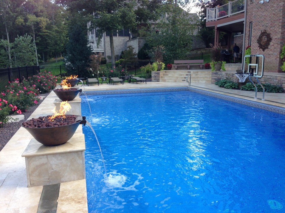 Ejemplo de piscina con fuente tradicional grande rectangular en patio trasero con suelo de baldosas