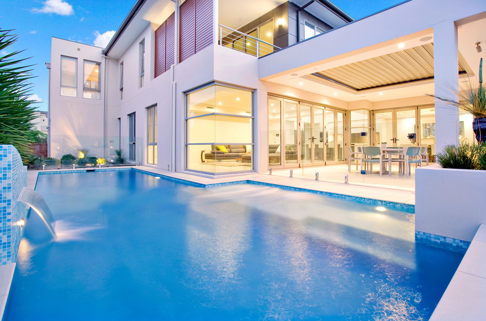 Idee per una grande piscina monocorsia minimal personalizzata dietro casa con pavimentazioni in pietra naturale