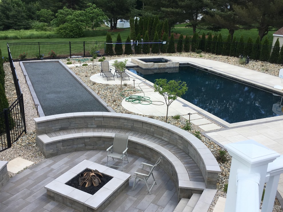Modelo de piscina infinita minimalista de tamaño medio rectangular en patio trasero con adoquines de hormigón