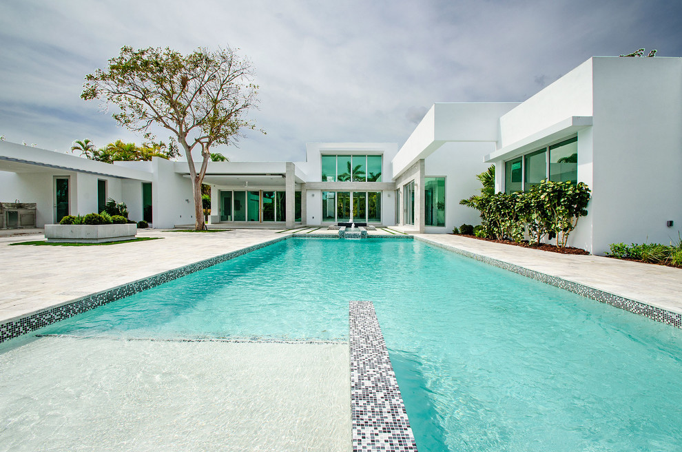 Ispirazione per una grande piscina moderna rettangolare dietro casa con fontane e pavimentazioni in pietra naturale