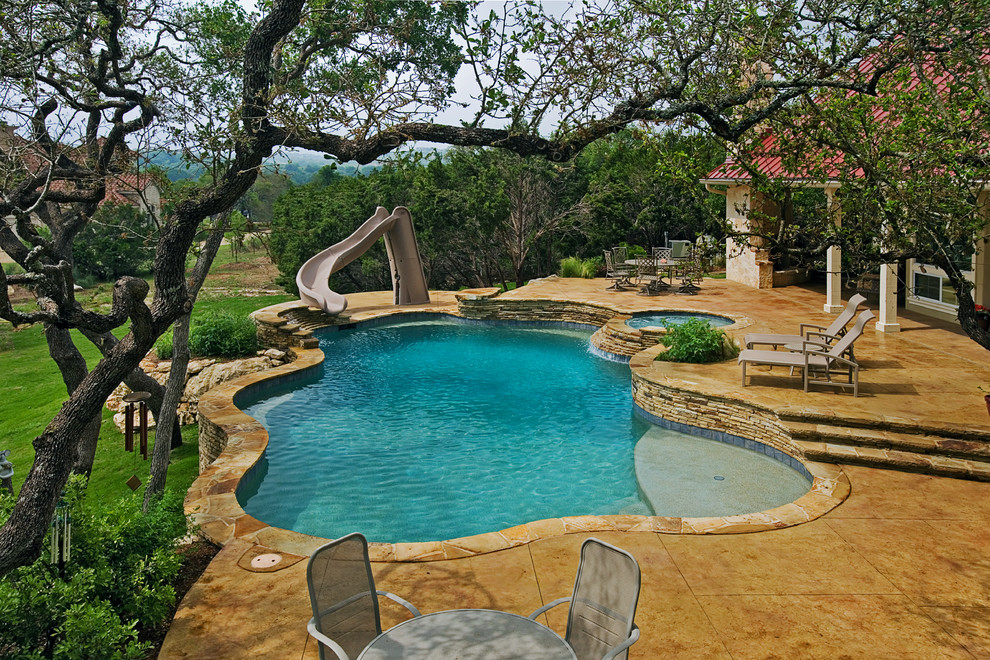 This is an example of a medium sized rustic back custom shaped natural swimming pool in Other with a water slide and stamped concrete.