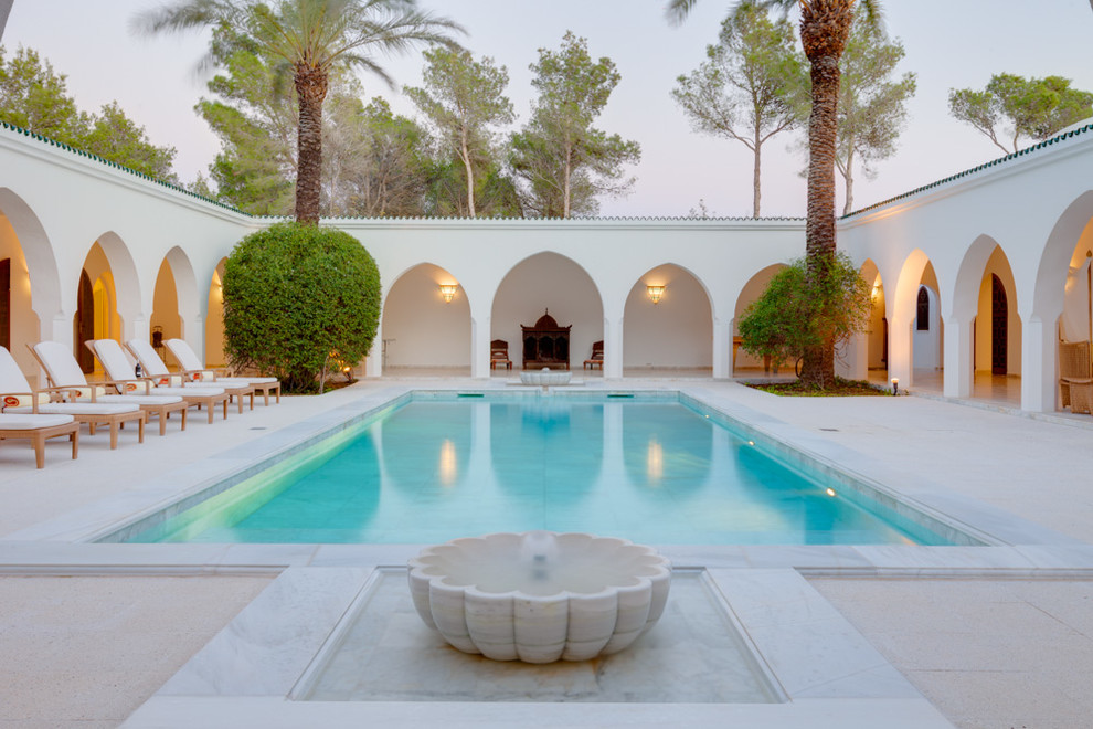 Foto de piscina con fuente mediterránea grande rectangular en patio con adoquines de piedra natural