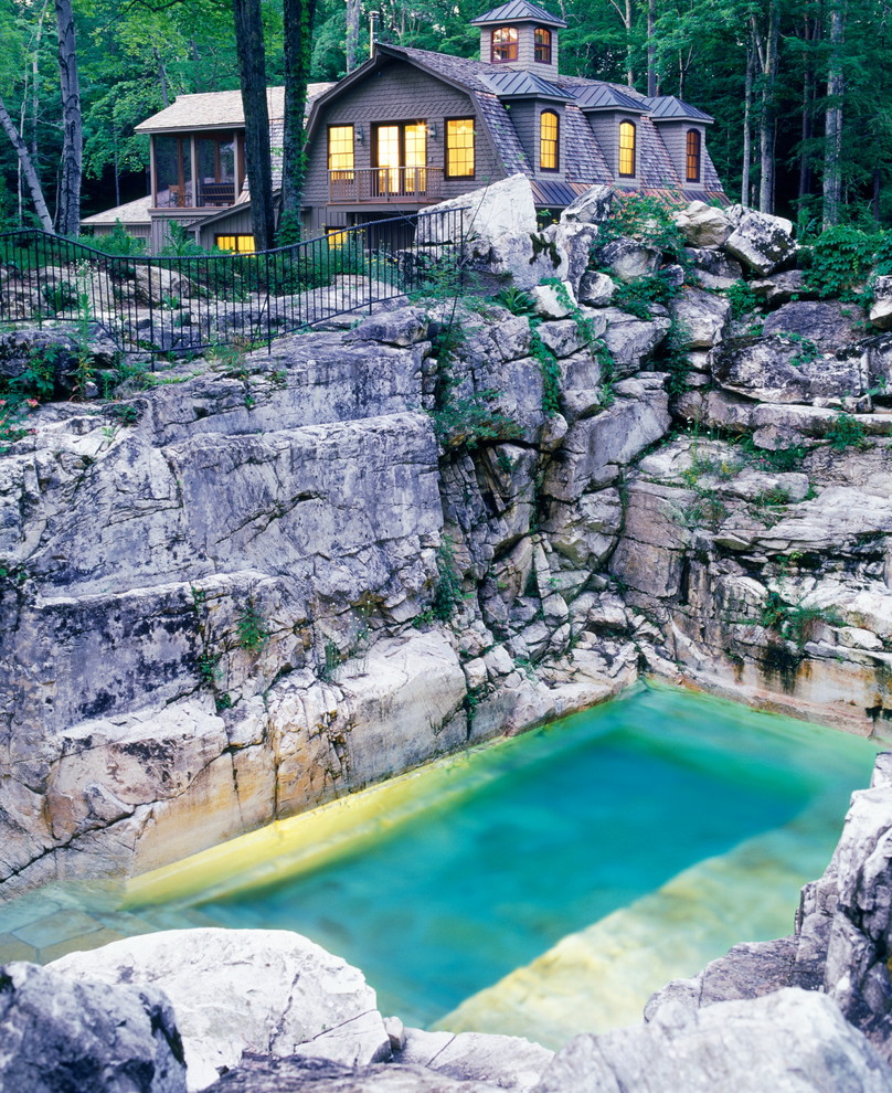 Idée de décoration pour une grande piscine naturelle et arrière design sur mesure avec un point d'eau et des pavés en pierre naturelle.
