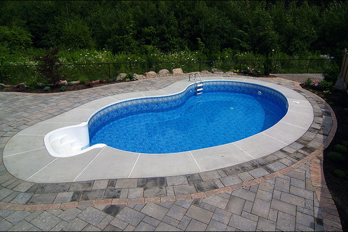 Diseño de piscina alargada clásica renovada de tamaño medio a medida en patio trasero con adoquines de hormigón