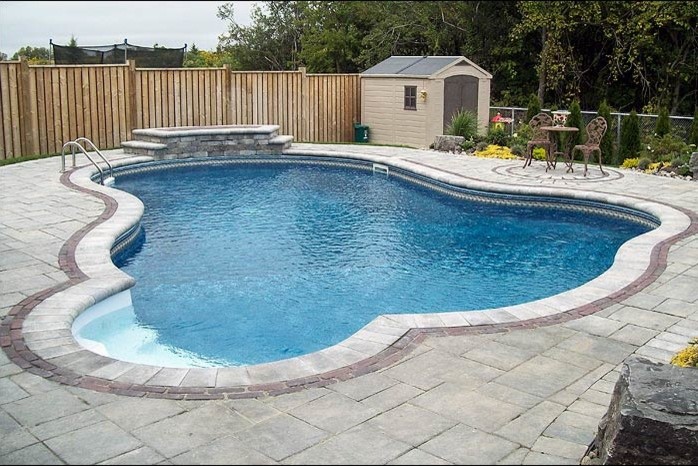 Medium sized classic back custom shaped lengths swimming pool in Toronto with concrete paving.