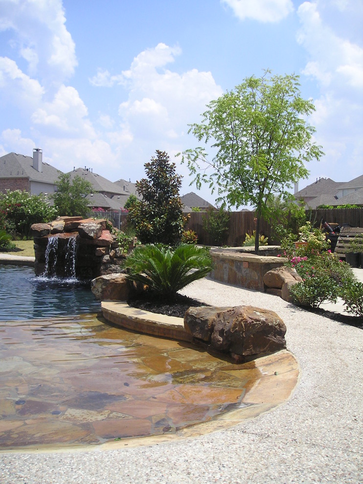 На фото: большой естественный бассейн произвольной формы на заднем дворе в стиле кантри с фонтаном и покрытием из бетонных плит